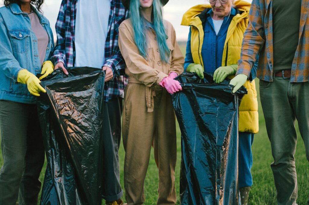 People Standing on Green Grass Field while Holding Plastic Bags